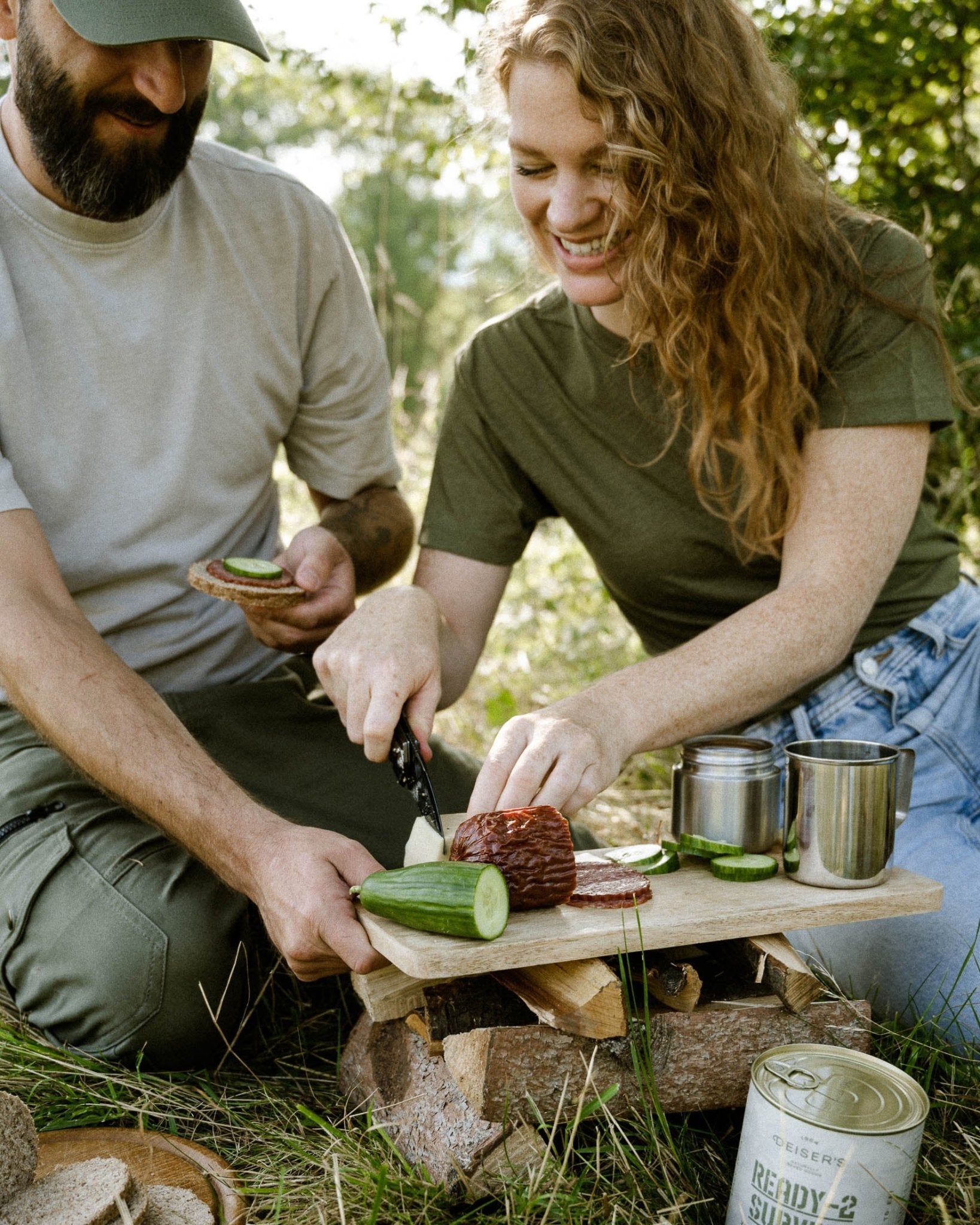 Ein Mann und eine Frau sitzen in der Wiese, vor sich ein Deiser's Dosenbrot und sie machen gemeinsam belegte Brote.