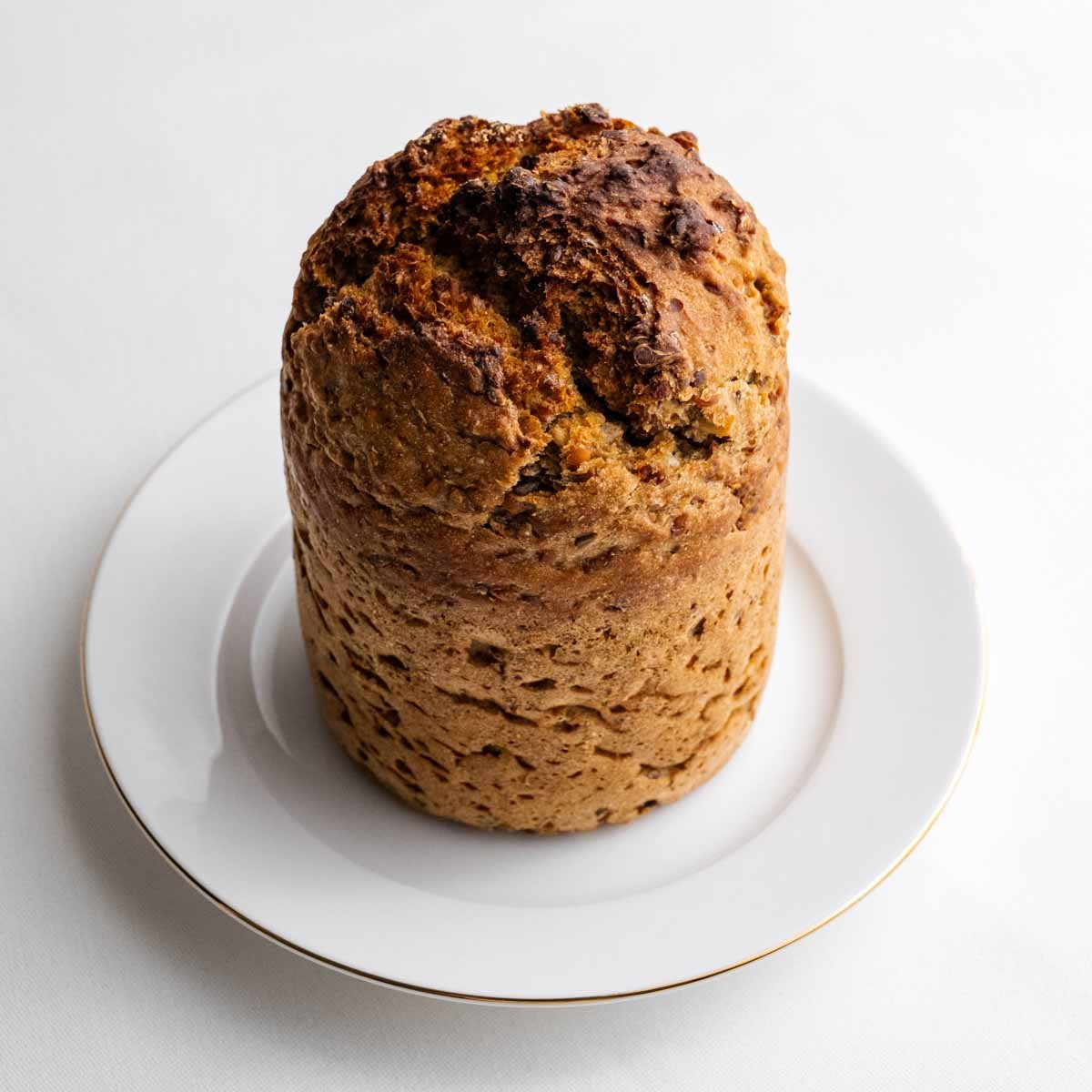 Das Eiweißbrot aus der Dose genommen von Deiser's naturally baked goods im Ganzen, auf einem weißen Teller mit goldenem Rand.