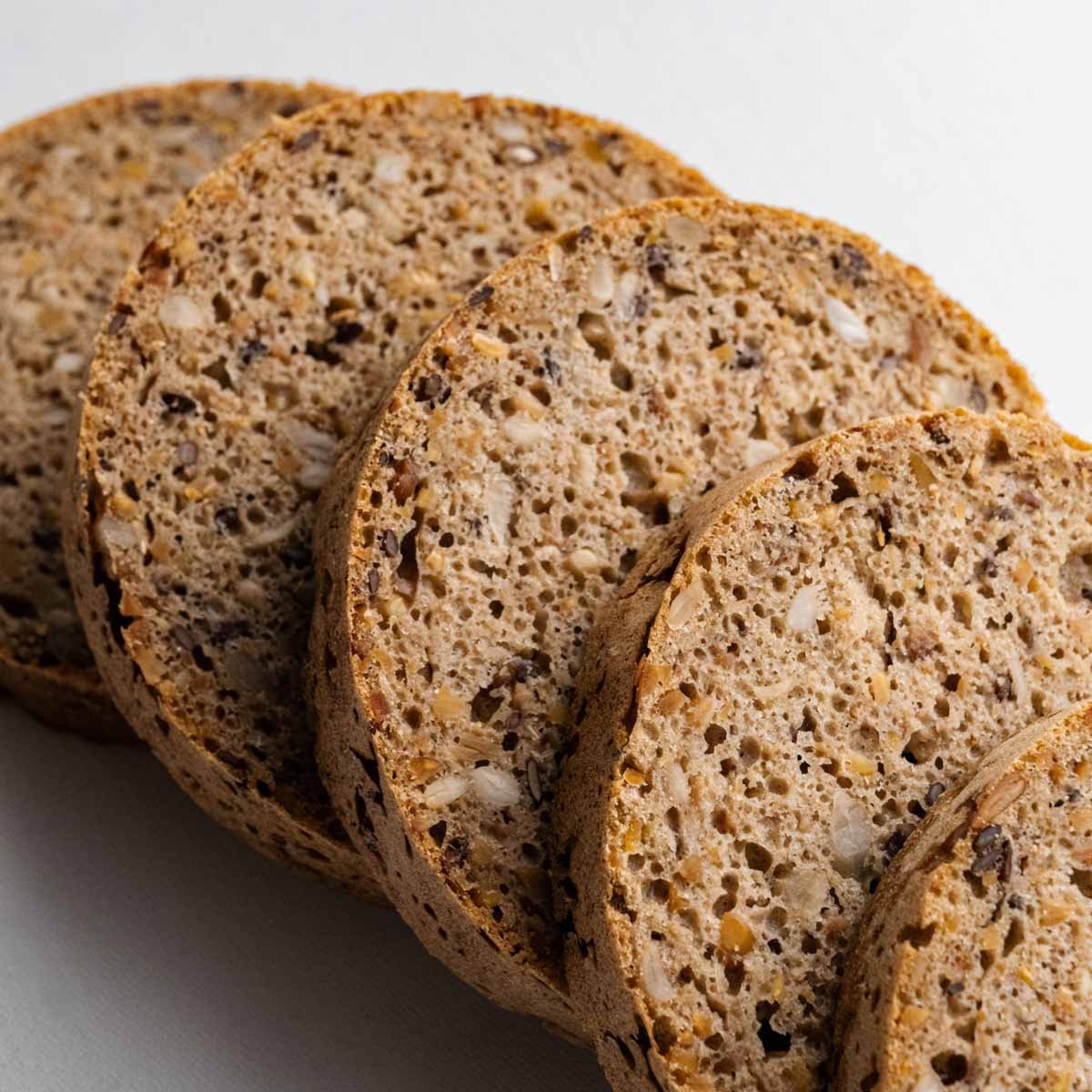 Das Eiweißbrot aus der Dose von Deiser's Dosenbrot in runde Brotscheiben aufgeschnitten und gefächert, die feine Krume mit den Leinsamen, dem Sojaschrot und den Sonnenblumenkernen ist gut zu sehen.