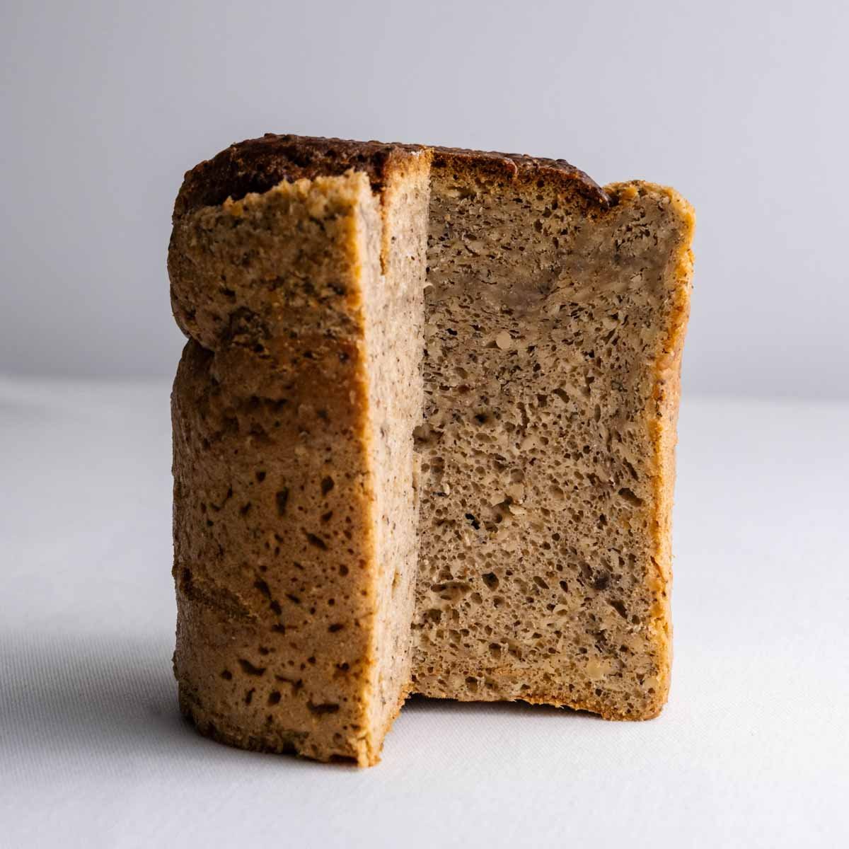 Das Hanfbrot aus der Dose von Deiser's naturally baked goods angeschnitten, sodass die feine Krume mit den geschälten Hanfsamen und Brotgewürzen gut zu sehen ist.