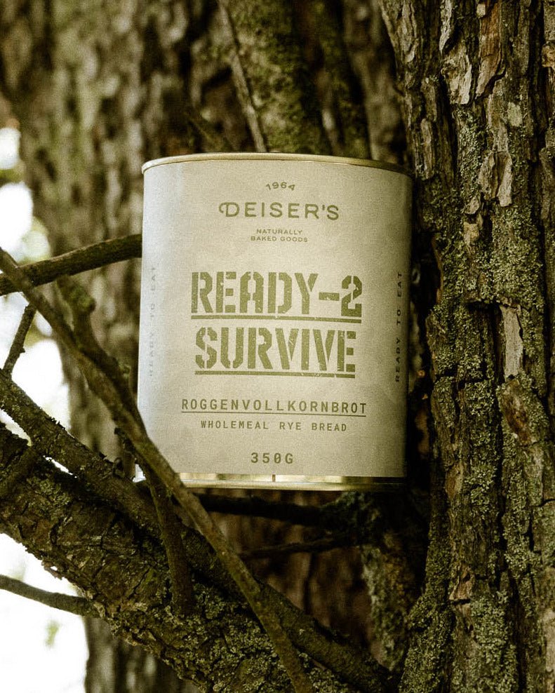 Eine Dose Ready-2-Survive Roggelvollkornbrot steht auf einer Astgabel eines Baumes. 