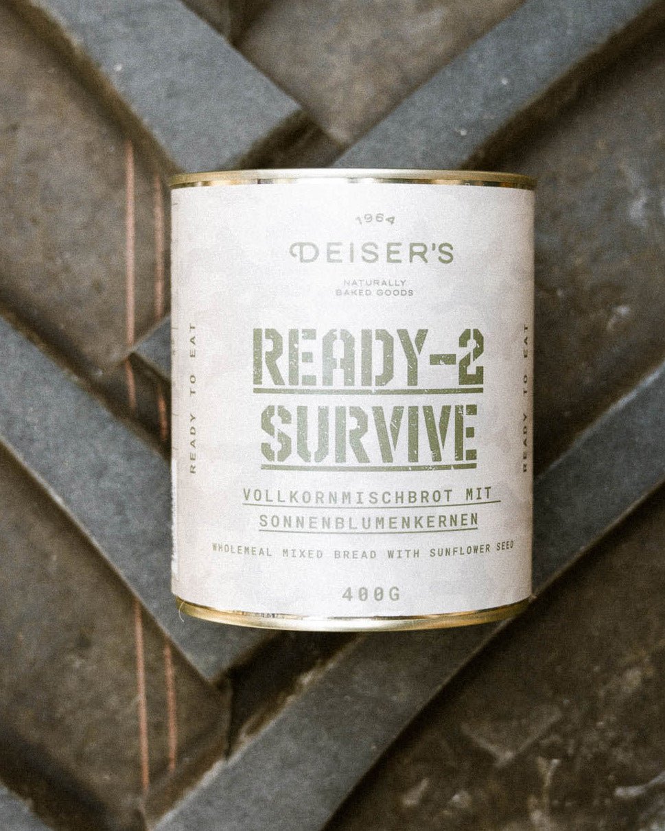 Eine Dose Ready-2-Survive Vollkornmischbrot mit Sonnenblumenkernen liegt auf einem Traktorreifen Hintergrund. 